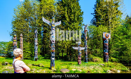 Les Totems colorés représentant des symboles religieux et d'art de la côte ouest les peuples autochtones placés dans le parc Stanley à Vancouver, BC, Canada Banque D'Images