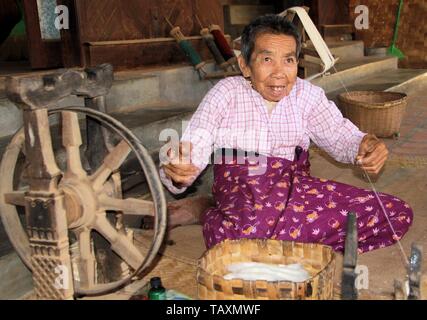 BAGAN, MYANMAR - 21 décembre. 2015 : ancienne filature homme birman en face d'une simple hutte avec roue en bois ancien Banque D'Images