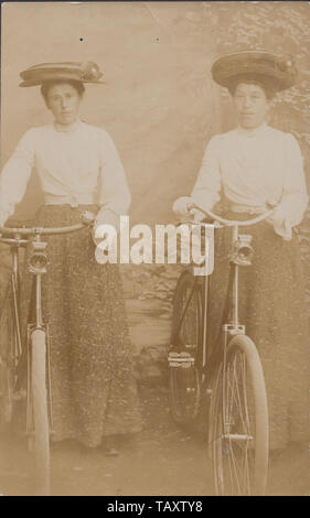 Vintage Edwardian Carte postale photographique montrant deux dames élégantes avec leur vélo. Banque D'Images