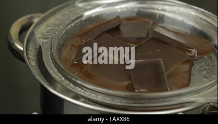 Faire fondre le chocolat noir dans un bol sur un bain d'eau bouillante dans la casserole sur la cuisinière. Concept pour faits de chocolat. Chocolat en vrac dans un pot de fusion. Close-up shot Banque D'Images