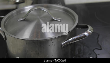 L'eau bouillante dans la casserole recouverte d'un couvercle dans la cuisine. Banque D'Images