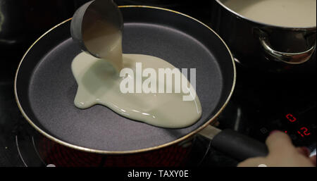 Le processus de cuisson de crêpes maison. Femme grases la poêle chaude verse la pâte à crêpes avec louche. Aliments gras. Flapjacks appétissante la cuisson dans une poêle. Close-up shot Banque D'Images