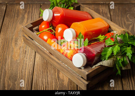 Jus de fruits frais smoothies à partir d'une variété de légumes Carottes Betteraves tomates apple les bouteilles en boîte en bois fond brun. Banque D'Images