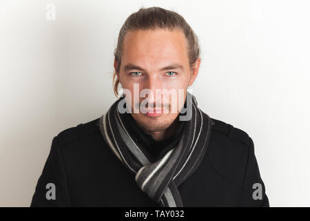 Young adult Asian man in black manteau et écharpe en laine se tient sur mur blanc arrière-plan. Close up studio portrait Banque D'Images