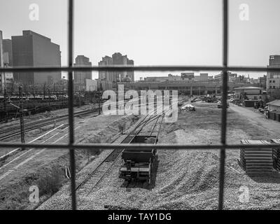 Séoul, Corée du Sud - Mars 2018 : photo prise par derrière une grille, d'un point de vue de la gare avec rails et gravier. ​​Background ville. Noir et blanc. Banque D'Images