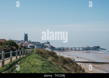 Cromer, UK - 20 avril, 2019 : les gens marcher sur un chemin côtier le long de la plage de Cromer, jetée de la ville et sur l'arrière-plan. C'est une ville balnéaire de Cromer j Banque D'Images