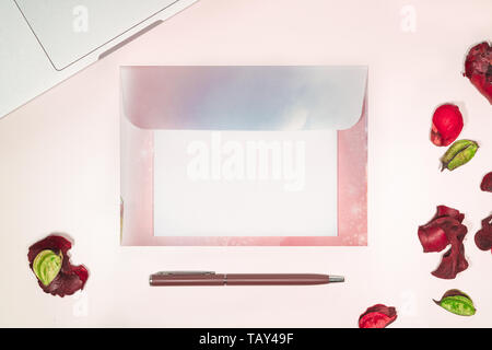 Espace de travail féminin avec lettre ouverte vierge ordinateur portable matériel d'écriture et rose fleurs séchées vue supérieure Banque D'Images