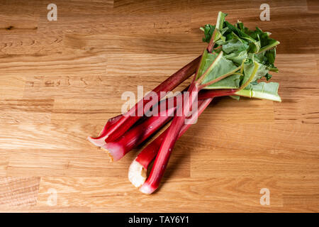 Les tiges de rhubarbe rouge frais sur une table en bois Banque D'Images