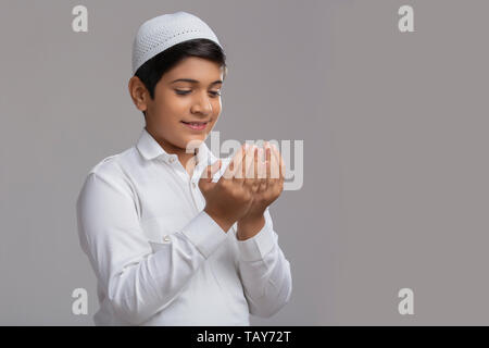 Jeune garçon musulman wearing cap priant et souriant Banque D'Images