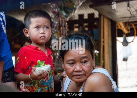 Mékong, Laos - Dec 2016 : Portrait d'un enfant de manger pomelo et sa grand-mère, pensant à maison flottante. Banque D'Images