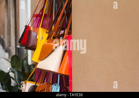 Gros plan horizontal d'un grand nombre de sac à main femme en cuir coloré sacs suspendu par la porte à l'écran de mode de rue petit magasin copyspace disponible Banque D'Images