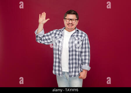 Portrait of happy handsome middle aged man in casual chemise à carreaux, les lunettes standing looking at camera, agitant sa main et d'accueil. en Banque D'Images