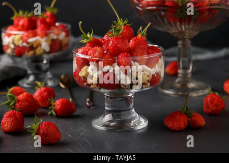 Dessert avec des fraises, fromage cottage et de gobelets en verre de biscuit sur un fond sombre, photo horizontale Banque D'Images