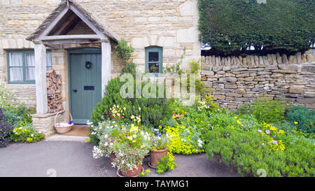 Jardin de devant avec des fleurs en fleurs, d'herbes par un cottage en pierre dans un village rural. Banque D'Images