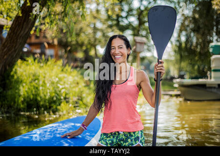 Mid adult woman se prépare pour paddleboarding. Banque D'Images