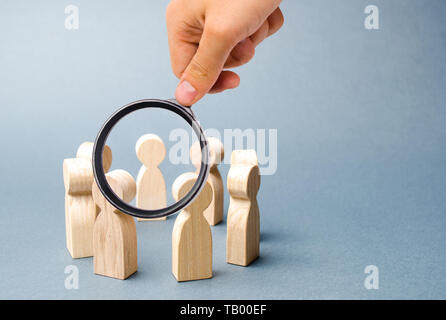 Loupe à la recherche de personnes à former un cercle sur un fond gris. Figures en bois de personnes. Un cercle de personnes. La discussion, la coopération, c Banque D'Images