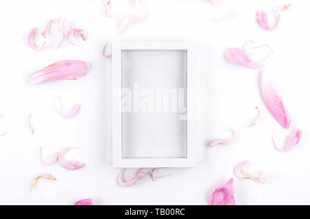 La composition de l'été. Cadre blanc vide de pétales de rose autour de la pivoine blanche sur fond de papier. Maison de vacances concept, carte de vœux. Mise à plat, vue du dessus, Banque D'Images