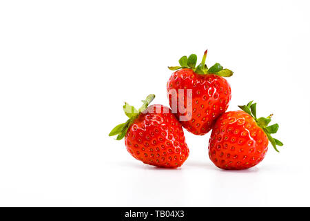 Close up de trois fraises mûres en équilibre sur l'autre. Tous sont isolés sur un fond blanc avec espace pour copier sur la droite. Banque D'Images