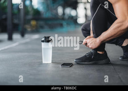 Homme attachant lacets de sneakers in gym Banque D'Images
