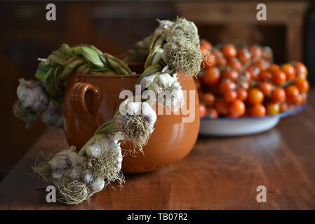 La vie toujours avec de l'ail, la tomate et le pot en argile sur une table en bois dans le style du pays Banque D'Images