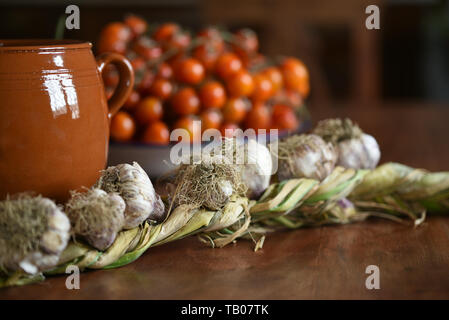 La vie toujours avec de l'ail, la tomate et le pot en argile sur une table en bois dans le style du pays Banque D'Images