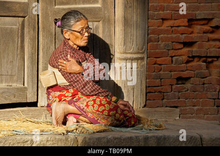 Les femmes âgées (porter des harnais dorsal) assis dans le soleil s'abaisser d'accueil, dans la vieille ville de Dhulikhel, Népal Banque D'Images