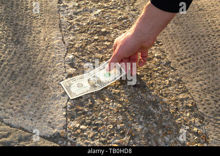 L'homme chanceux est de trouver l'argent dans la rue sur le plancher. L'heureuse personne a trouvé vingt dollars. Une chance pour un pari. Jackpot. Casino. Banque D'Images