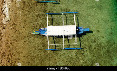 Bateau philippin traditionnel sur la surface de l'azur de l'eau dans le lagon. Vue de dessus du bateau de drone. Banque D'Images