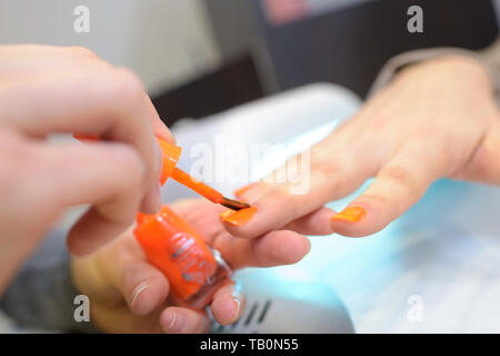 Peinture femme en orange les ongles Banque D'Images