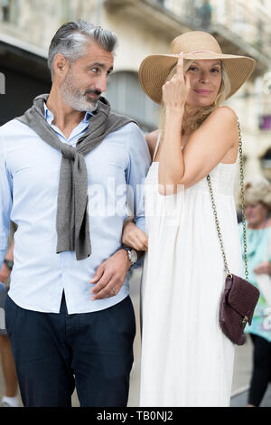 Senior couple in city street woman tipping son chapeau Banque D'Images
