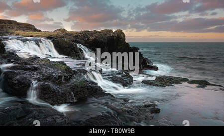 Coucher de soleil sur Dunseverick Cascades, Bushmills, comté d'Antrim, en Irlande du Nord Banque D'Images