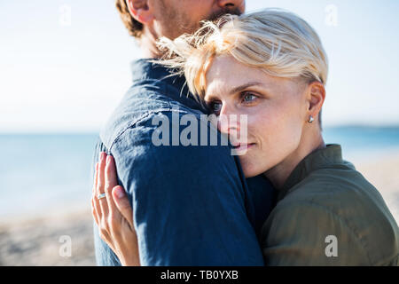 Section médiane de jeunes couples debout à l'extérieur sur la plage, embrassant. Copier l'espace. Banque D'Images