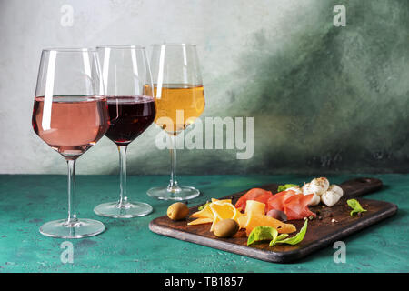 Verres de différentes sortes de vin avec des collations sur table couleurs Banque D'Images