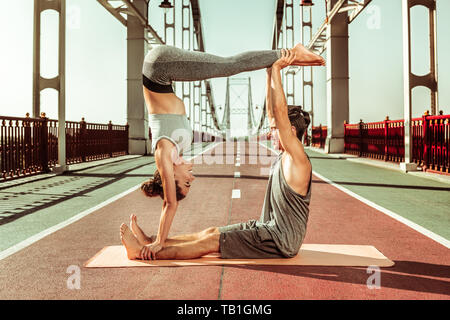 Jeune homme et femme faisant un jedi fort acroyoga poser Banque D'Images