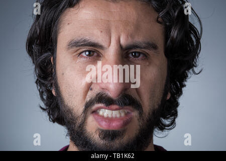 Homme en colère avec Barbe et cheveux longs pleurer Looking at Camera Banque D'Images