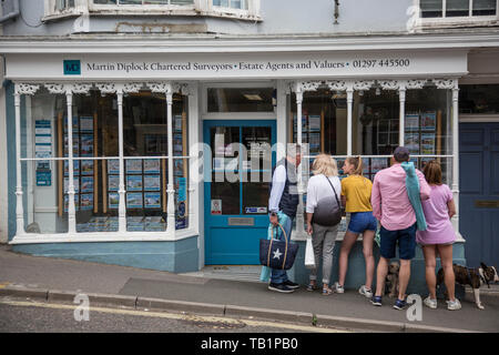 Famille à la recherche de propriétés à vendre annoncés dans un agent immobilier dans la fenêtre à l'ouest du Dorset, Angleterre, Royaume-Uni Banque D'Images