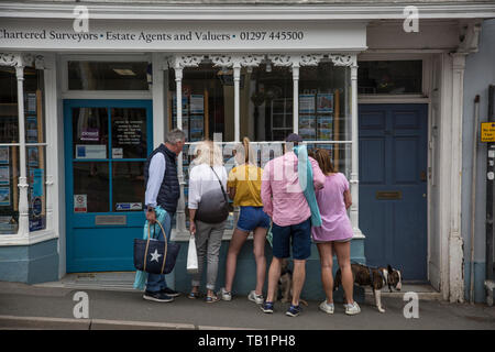 Famille à la recherche de propriétés à vendre annoncés dans un agent immobilier dans la fenêtre à l'ouest du Dorset, Angleterre, Royaume-Uni Banque D'Images