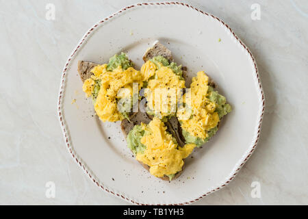 Oeufs brouillés avec de l'avocat sur toast de pain pour le petit-déjeuner. L'alimentation biologique. Banque D'Images
