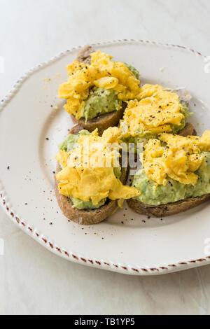 Oeufs brouillés avec de l'avocat sur toast de pain pour le petit-déjeuner. L'alimentation biologique. Banque D'Images