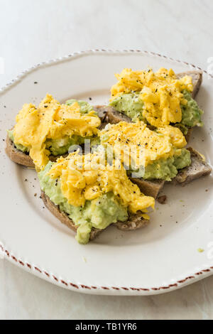 Oeufs brouillés avec de l'avocat sur toast de pain pour le petit-déjeuner. L'alimentation biologique. Banque D'Images