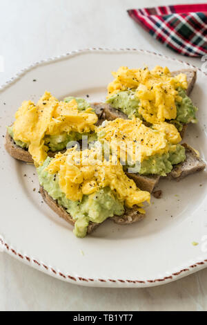 Oeufs brouillés avec de l'avocat sur toast de pain pour le petit-déjeuner. L'alimentation biologique. Banque D'Images
