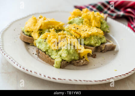 Oeufs brouillés avec de l'avocat sur toast de pain pour le petit-déjeuner. L'alimentation biologique. Banque D'Images