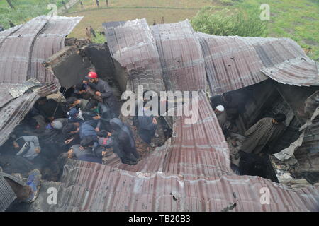 Cachemire, l'Inde du Sud. 23 mai, 2019. Les villageois du cachemire réunis autour d'une maison endommagée après un gunbattle dans tral, au sud de Srinagar, au Cachemire sous contrôle indien, le vendredi 24 mai 2019. Les forces gouvernementales dans le Cachemire sous contrôle indien tué un haut commandant de militants liés à al-Qaïda dans la région contestée. Credit : Faisal Bhat/Pacific Press/Alamy Live News Banque D'Images
