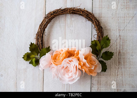High angle portrait d'une petite couronne de fleurs avec du papier rose saumon pâle et roses. Banque D'Images