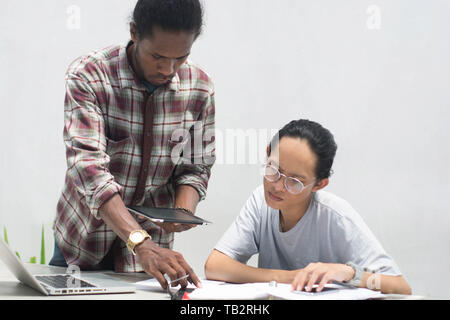 Deux ami avec différents groupes ethniques travaillent ensemble avec ordinateur portable et tablette aborder quelque chose, deux jeune homme travailler et étudier ensemble Banque D'Images
