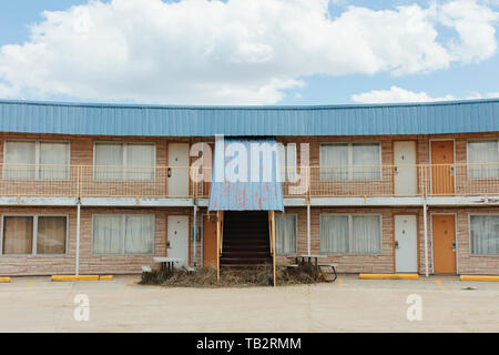 Motel abandonné bâtiment avec un auvent de métal rouillé, tiré les rideaux aux fenêtres, et tumbleweed autour de la procédure. Banque D'Images