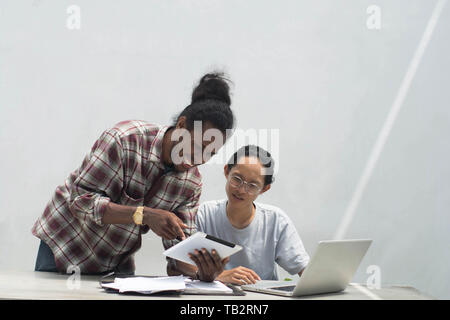 Deux ami avec différents groupes ethniques travaillent ensemble avec ordinateur portable et tablette aborder quelque chose, deux jeune homme travailler et étudier ensemble Banque D'Images
