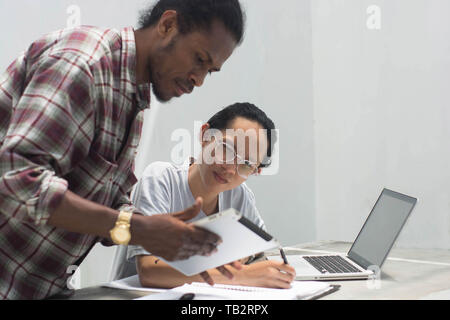Deux ami avec différents groupes ethniques travaillent ensemble avec ordinateur portable et tablette aborder quelque chose, deux jeune homme travailler et étudier ensemble Banque D'Images