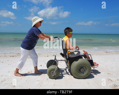 Femme handicapée en fauteuil roulant de plage apprécie le soleil et le sable à l'Honeymoon Island State Park à Dunedin, en Floride, USA, le 10 mai 2019, © Katharine Andrioti Banque D'Images