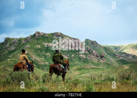 Deux hommes de l'équitation. Les pâturages d'été dans une vallée intermontagneux. Kazakhstan Banque D'Images